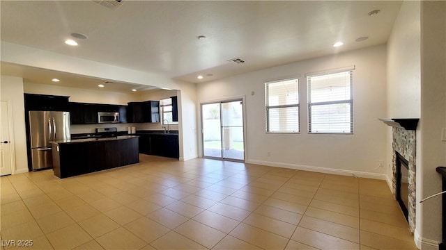 145 Forest Crossing Ct, Las Vegas, NV 89148 - kitchen with appliances with stainless steel finishes, dark cabinetry, a center island, light tile patterned flooring, and open floor plan