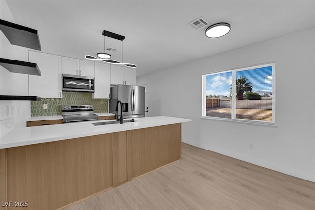 1108 Putnam Ave, North Las Vegas, NV 89030 - kitchen featuring stainless steel appliances, backsplash, open shelves, light countertops, and light wood-type flooring