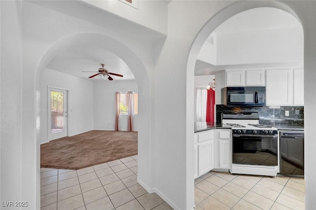 900 Heavenly Hills Ct Unit 114, Las Vegas, NV 89145 - kitchen featuring black appliances, light colored carpet, light tile patterned floors, white cabinetry, and arched walkways