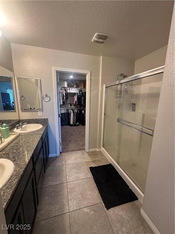 7636 Bandon Cliffs St, North Las Vegas, NV 89084 - full bath with a shower stall, a textured ceiling, a walk in closet, double vanity, and tile patterned floors