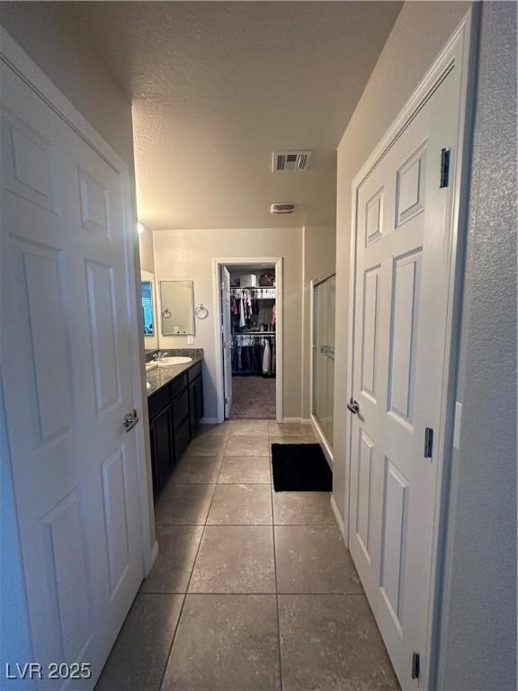 7636 Bandon Cliffs St, North Las Vegas, NV 89084 - bathroom featuring a spacious closet, vanity, a stall shower, and tile patterned flooring
