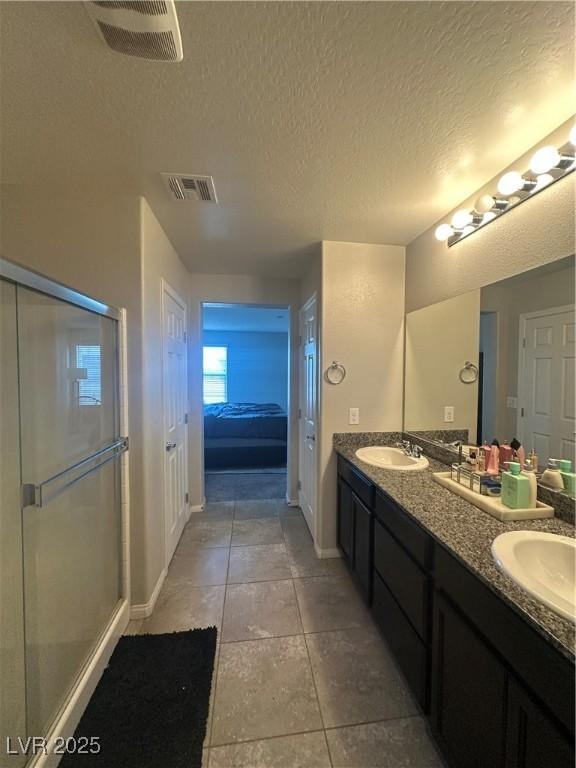 7636 Bandon Cliffs St, North Las Vegas, NV 89084 - bathroom with double vanity, tile patterned floors, a textured ceiling, and a stall shower