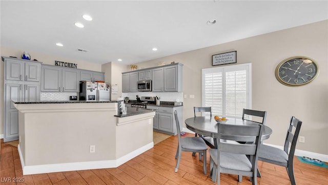 8139 Skytop Ledge Ave, Las Vegas, NV 89178 - kitchen with appliances with stainless steel finishes, gray cabinets, light wood-style flooring, a kitchen island, and tasteful backsplash