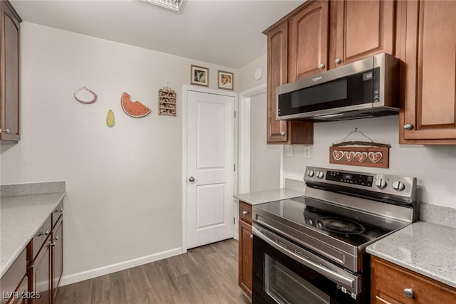 531 New Mexico St, Boulder City, NV 89005 - kitchen with stainless steel appliances, wood finished floors, brown cabinetry, and light stone countertops