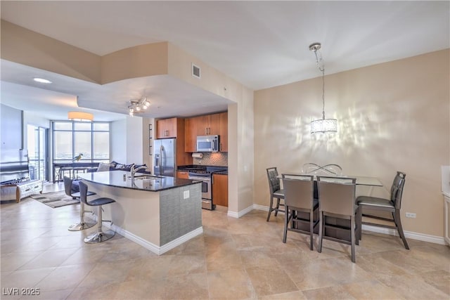 200 W Sahara Ave Unit 2210, Las Vegas, NV 89102 - kitchen with appliances with stainless steel finishes, brown cabinets, dark countertops, tasteful backsplash, and a breakfast bar
