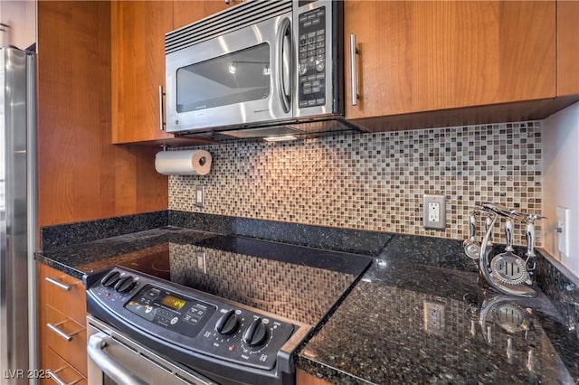 200 W Sahara Ave Unit 2210, Las Vegas, NV 89102 - kitchen with stainless steel appliances, brown cabinetry, tasteful backsplash, and dark stone counters