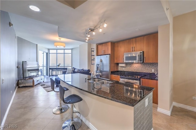 200 W Sahara Ave Unit 2210, Las Vegas, NV 89102 - kitchen featuring appliances with stainless steel finishes, brown cabinetry, tasteful backsplash, a kitchen bar, and dark stone counters