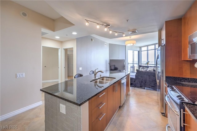 200 W Sahara Ave Unit 2210, Las Vegas, NV 89102 - kitchen with open floor plan, appliances with stainless steel finishes, a kitchen island with sink, brown cabinetry, and dark stone countertops