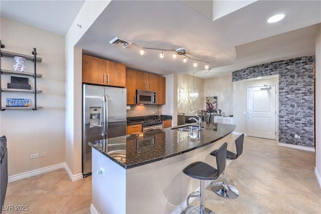 200 W Sahara Ave Unit 2210, Las Vegas, NV 89102 - kitchen featuring stainless steel appliances, brown cabinets, a kitchen bar, decorative backsplash, and a center island with sink