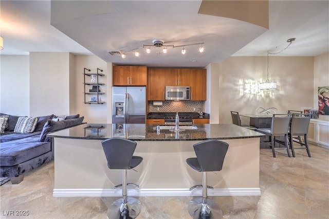 200 W Sahara Ave Unit 2210, Las Vegas, NV 89102 - kitchen featuring stainless steel appliances, brown cabinetry, decorative backsplash, a kitchen breakfast bar, and a kitchen island with sink