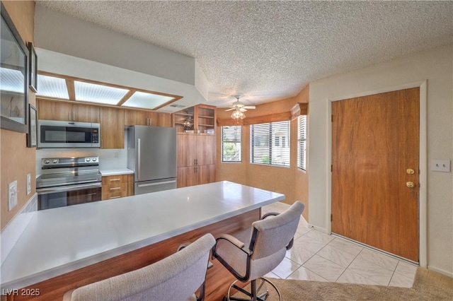 1201 N Buffalo Dr Unit 202, Las Vegas, NV 89128 - kitchen with appliances with stainless steel finishes, a breakfast bar, brown cabinets, a peninsula, and light countertops