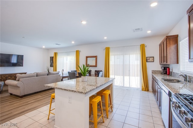10435 Rose Palisade St, Las Vegas, NV 89141 - kitchen featuring a kitchen breakfast bar, light tile patterned flooring, stainless steel range with gas cooktop, a kitchen island, and light stone countertops