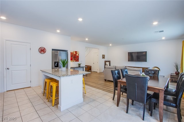 10435 Rose Palisade St, Las Vegas, NV 89141 - kitchen with stainless steel refrigerator with ice dispenser, a center island, a breakfast bar, recessed lighting, and light stone countertops