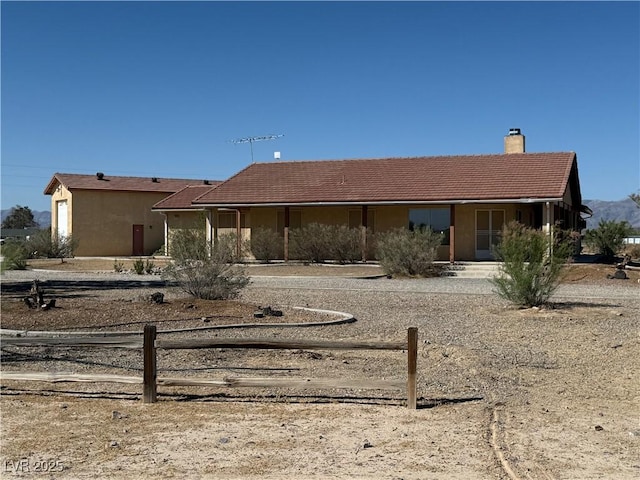 3090 N Woodchips Rd, Pahrump, NV 89060 - view of front facade with a chimney, covered porch, stucco siding, and a tiled roof