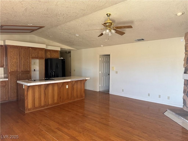 3090 N Woodchips Rd, Pahrump, NV 89060 - kitchen with black appliances, a ceiling fan, dark wood-style flooring, tile countertops, and brown cabinets