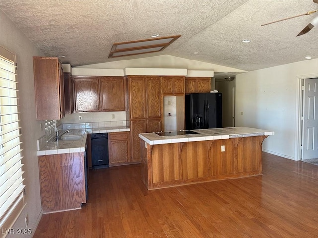 3090 N Woodchips Rd, Pahrump, NV 89060 - kitchen with black appliances, tile counters, dark wood-style floors, lofted ceiling, and a kitchen island
