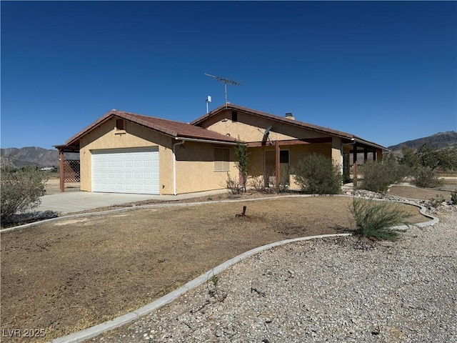 3090 N Woodchips Rd, Pahrump, NV 89060 - view of front of house featuring a garage, stucco siding, a mountain view, and driveway