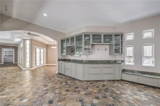 2017 Slow Wind St, Las Vegas, NV 89134 - kitchen featuring dark countertops, arched walkways, a ceiling fan, glass insert cabinets, and healthy amount of natural light