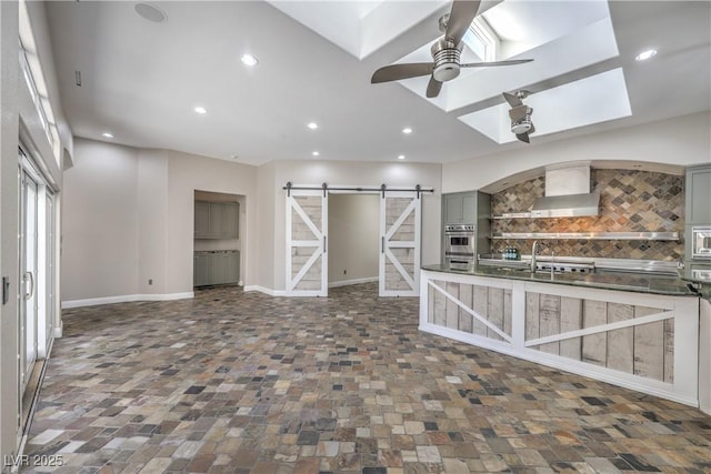 2017 Slow Wind St, Las Vegas, NV 89134 - kitchen with a barn door, backsplash, a ceiling fan, wall chimney range hood, and gray cabinetry