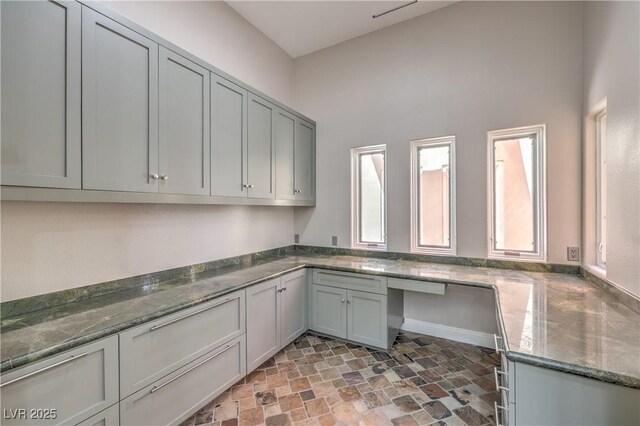2017 Slow Wind St, Las Vegas, NV 89134 - kitchen with stone finish floors, dark stone counters, gray cabinetry, and a towering ceiling
