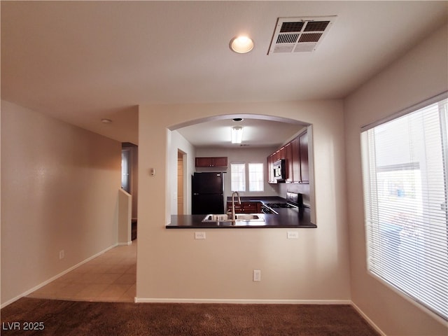 9069 Tantalizing Ave, Las Vegas, NV 89149 - kitchen featuring freestanding refrigerator, stainless steel microwave, dark countertops, arched walkways, and stove