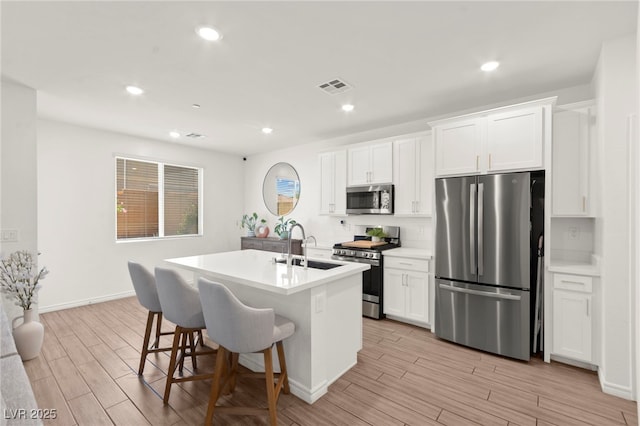 9743 Mojave Mountain St, Las Vegas, NV 89166 - kitchen with stainless steel appliances, light wood finished floors, a center island with sink, a kitchen breakfast bar, and recessed lighting