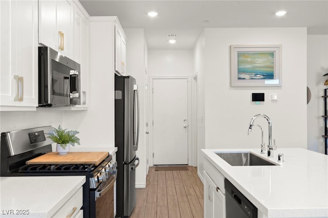 9743 Mojave Mountain St, Las Vegas, NV 89166 - kitchen with stainless steel appliances, light wood finished floors, white cabinets, light countertops, and a kitchen island with sink