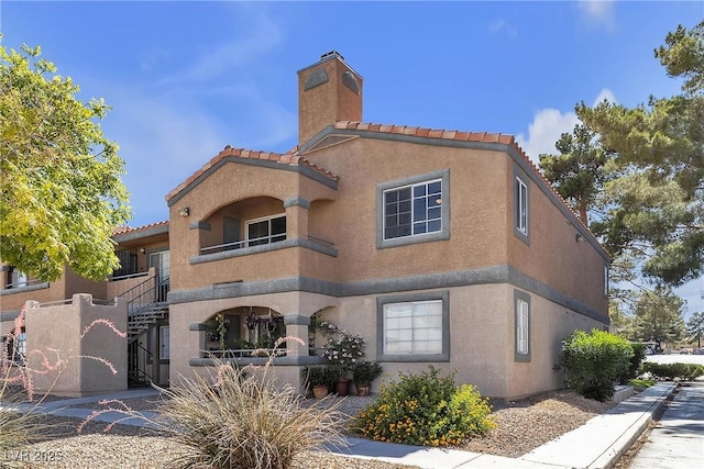 220 Mission Catalina Ln Unit 208, Las Vegas, NV 89107 - view of front of house with a chimney, a tiled roof, and stucco siding