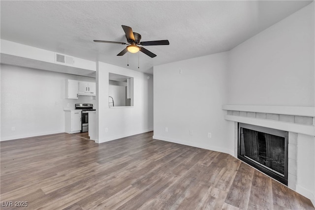 220 Mission Catalina Ln Unit 208, Las Vegas, NV 89107 - unfurnished living room featuring ceiling fan, a fireplace, wood finished floors, and a textured ceiling