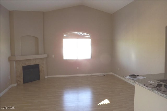 75 N Valle Verde Dr Unit 225, Henderson, NV 89074 - unfurnished living room featuring light wood finished floors, a fireplace, and vaulted ceiling