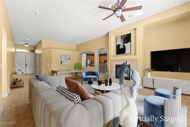 9685 Stonily Ln, Las Vegas, NV 89178 - living area featuring ceiling fan, light tile patterned flooring, arched walkways, and a glass covered fireplace