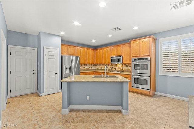 9685 Stonily Ln, Las Vegas, NV 89178 - kitchen with appliances with stainless steel finishes, tasteful backsplash, a center island with sink, light tile patterned floors, and light stone counters