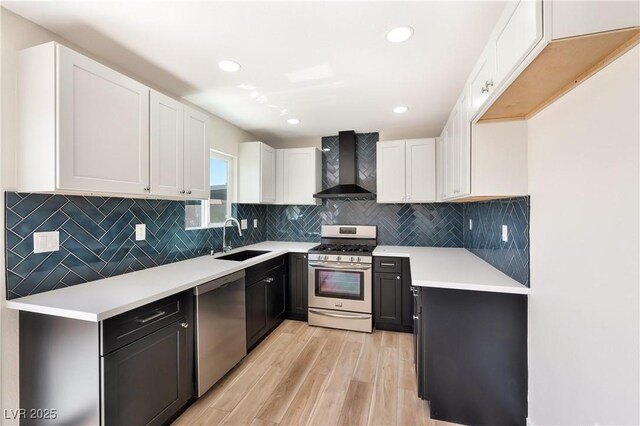 5004 Celebrity Cir, Las Vegas, NV 89119 - kitchen featuring wall chimney range hood, stainless steel appliances, light wood-style flooring, white cabinets, and recessed lighting