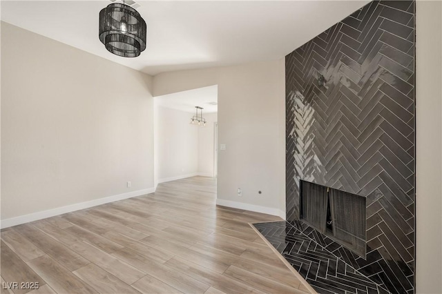 5004 Celebrity Cir, Las Vegas, NV 89119 - unfurnished living room with a tiled fireplace, light wood-type flooring, and a chandelier