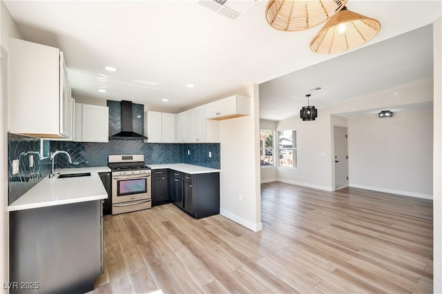 5004 Celebrity Cir, Las Vegas, NV 89119 - kitchen with stainless steel range with gas cooktop, wall chimney range hood, light wood finished floors, backsplash, and light countertops