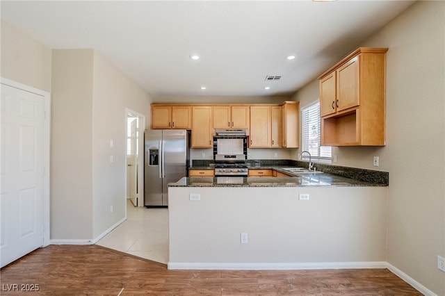 5282 Monterey Park Cir, Las Vegas, NV 89146 - kitchen featuring appliances with stainless steel finishes, light brown cabinetry, a peninsula, dark stone counters, and recessed lighting
