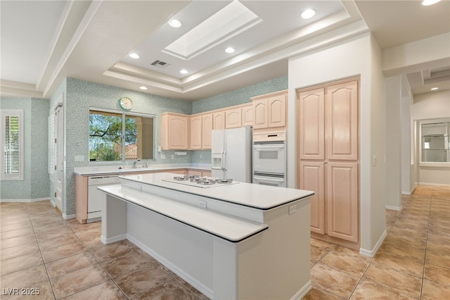 10548 Findlay Ave, Las Vegas, NV 89134 - kitchen featuring white appliances, a raised ceiling, light brown cabinetry, a kitchen island, and light countertops