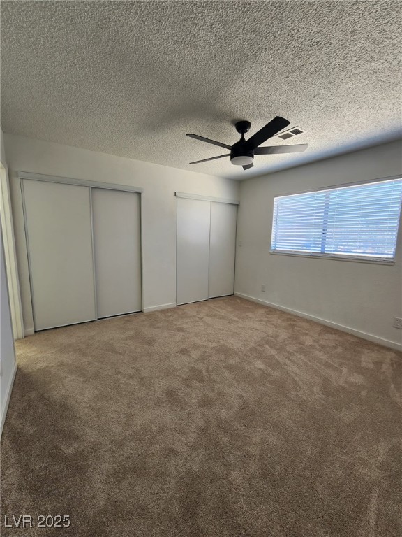 3318 Covey Ln, Las Vegas, NV 89115 - unfurnished bedroom featuring two closets, carpet flooring, a textured ceiling, and a ceiling fan