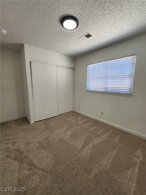 3318 Covey Ln, Las Vegas, NV 89115 - unfurnished bedroom featuring carpet flooring, a closet, and a textured ceiling