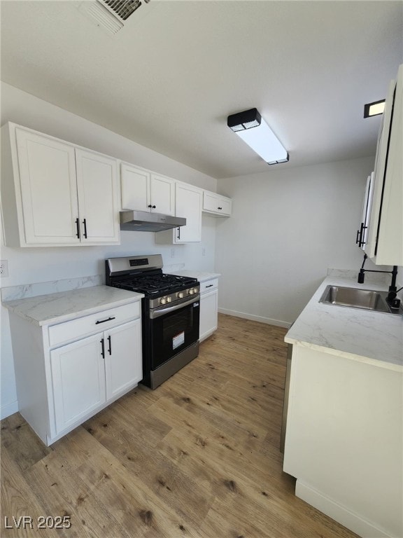 3318 Covey Ln, Las Vegas, NV 89115 - kitchen with stainless steel gas range oven, under cabinet range hood, light wood-type flooring, and white cabinets