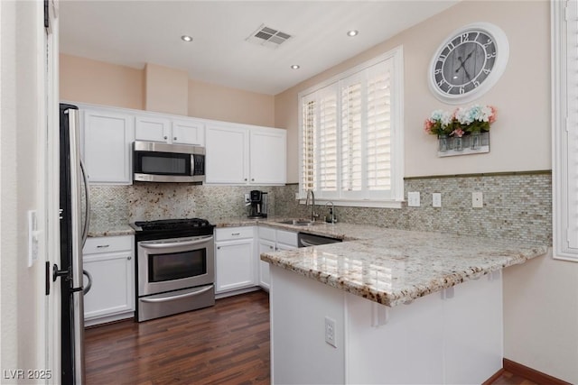 1839 Thunder Mountain Dr, Henderson, NV 89012 - kitchen with appliances with stainless steel finishes, a peninsula, white cabinetry, light stone countertops, and recessed lighting