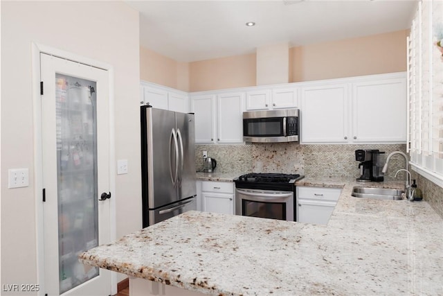 1839 Thunder Mountain Dr, Henderson, NV 89012 - kitchen with appliances with stainless steel finishes, a peninsula, white cabinets, decorative backsplash, and light stone countertops
