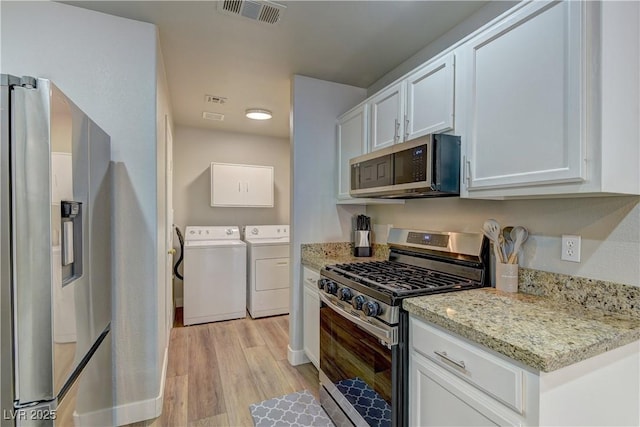 278 Star Cluster Cir, Las Vegas, NV 89145 - kitchen featuring appliances with stainless steel finishes, washer and dryer, light wood finished floors, and white cabinets