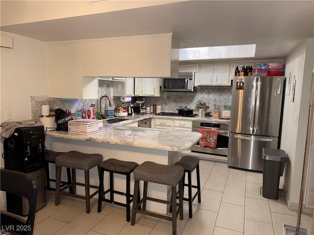 3447 One Nation Ave, Las Vegas, NV 89121 - kitchen with stainless steel appliances, a peninsula, backsplash, and a breakfast bar area