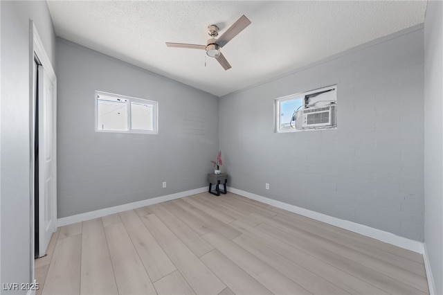 104 Stanford St, Las Vegas, NV 89107 - unfurnished bedroom with multiple windows, light wood-type flooring, cooling unit, a textured ceiling, and a ceiling fan