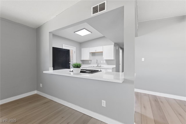 104 Stanford St, Las Vegas, NV 89107 - kitchen with fridge, wood finished floors, light countertops, white cabinetry, and a peninsula
