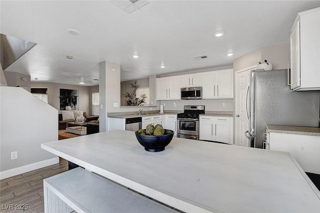 554 Haunts Walk Ave, Las Vegas, NV 89178 - kitchen with stainless steel appliances, white cabinets, wood finished floors, recessed lighting, and light countertops