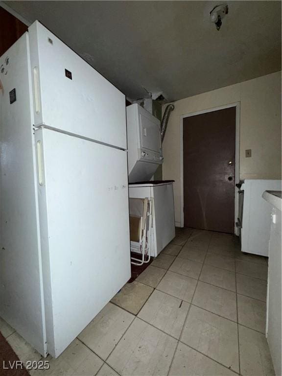 1104 High St, Ely, NV 89301 - kitchen with freestanding refrigerator, stacked washer and clothes dryer, and light tile patterned flooring