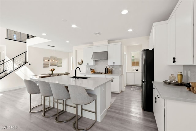 3058 Casarano Ct, Henderson, NV 89044 - kitchen featuring ventilation hood, freestanding refrigerator, a center island with sink, a kitchen breakfast bar, and light wood-type flooring
