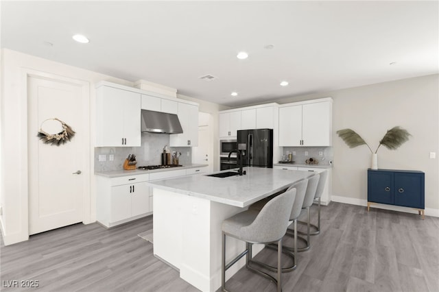 3058 Casarano Ct, Henderson, NV 89044 - kitchen with black fridge with ice dispenser, exhaust hood, white gas stovetop, light wood-style floors, and recessed lighting